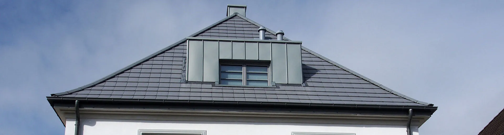 Ein modernisierter Altbau mit klaren Linien, neuer Fensterverglasung und einem grauen Satteldach. Die frisch renovierte Fassade wirkt gepflegt und stilvoll.