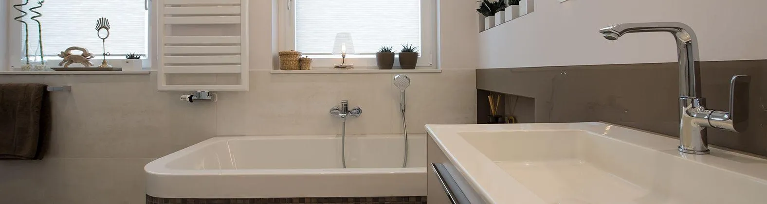 Ein modernes Badezimmer mit rechteckiger Badewanne, hellem Waschtisch und eleganter Armatur. 