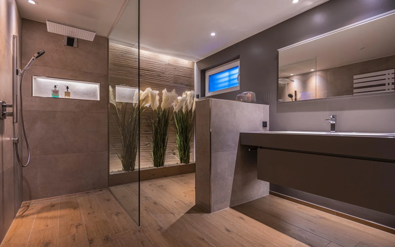 Ein luxuriöses Badezimmer mit bodengleicher Regendusche und stilvoller Holzoptik am Boden verströmt eine warme, einladende Atmosphäre.