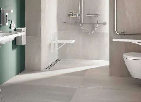 Barrierefreies Badezimmer mit Stützgriffen, unterfahrbaren Waschtisch, bodenebener Walk-In-Dusche und Dusch-WC.