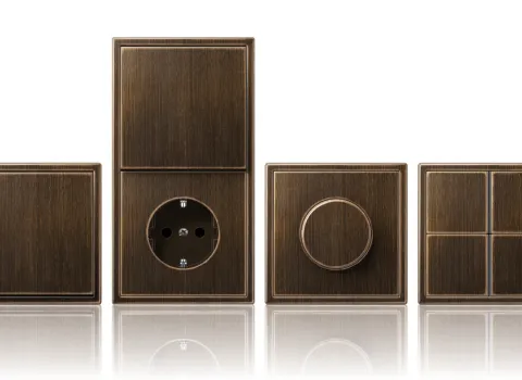 Verschiedene Schalter- und Steckdosenmodelle der Serie LS-990 von JUNG. Farbe Messing.