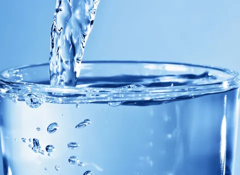 Nahaufnahme Glas, das mit sauberen Trinkwasser befüllt wird.