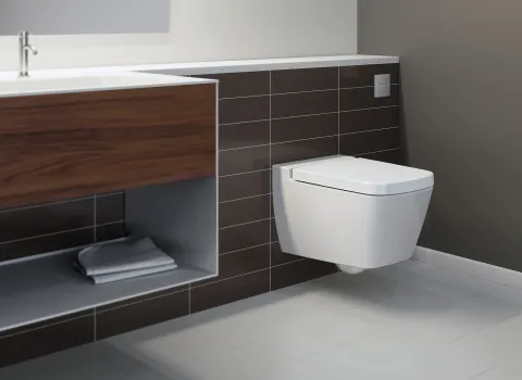 In diesem modernen Badezimmer fällt die wandhängende Toilette vor einer gefliesten Wand auf, über der der TECEflushpoint diskret installiert ist.