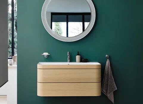Waschtisch Happy D.2 Plus mit hellem,holzfarbenen Unterbau vor grüner Wandund Deko.