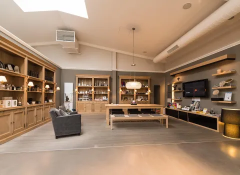 Ein großzügiger Showroom mit stilvollem Interieur, bestehend aus offenen Holzregalen, langen Holztischen und modernen Wandboards. 