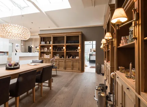 Ein stilvoller Showroom mit hellem Holzfußboden und klassischen Holzregalen, die mit Wellness- und Pflegeprodukten dekoriert sind.