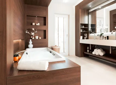 Ein luxuriöses Badezimmer mit freistehender Badewanne in Holzverkleidung, gefüllt mit schäumendem Wasser.