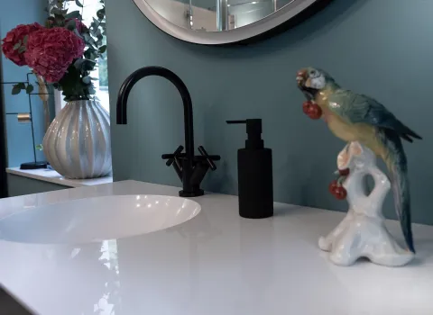 Nahaufnahme eines modernen Waschbeckens mit schwarzer Armatur und passendem Seifenspender auf einer glänzend weißen Oberfläche.