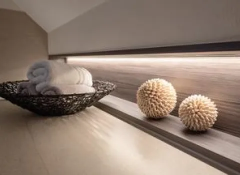 Ein stilvolles Badezimmer-Detail mit einem modernen Regal aus Holzoptik, beleuchtet durch eine dezente LED-Leiste.