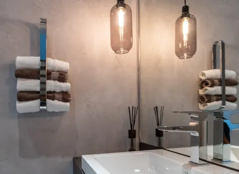 Ein modernes Badezimmer mit eleganter Wandstruktur und zwei gestapelten Handtuchrollen in Weiß und Braun.
