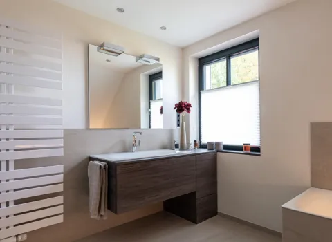 Ein modernes Badezimmer mit klaren Linien, ausgestattet mit einem dunklen Holzwaschtisch und integriertem Waschbecken.