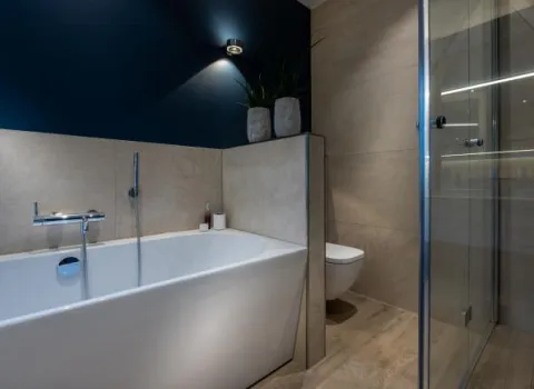 Ein modernes Badezimmer mit freistehender Badewanne, die elegant in eine Nische mit beigefarbenen Fliesen eingebettet ist.