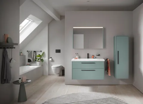 Modernes Badezimmer mit Badewanne und wandhängendem WC aus der Kollektion D-Code von Duravit sowie mintfarbenem Waschtischunterschrank unter Dachschräge.