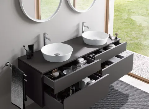Doppelwaschtisch mit Waschbecken und Armaturen von Duravit, runden Spiegeln und modernen Badmöbeln vor bodentiefem Fenster.