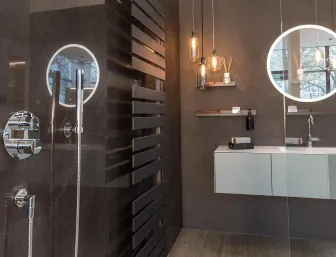 Ein stilvolles Badezimmer mit moderner Dusche, schwarzem Designheizkörper und eleganter Waschtischanlage. 
