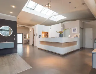 Ein großzügiger Empfangsbereich mit modernem Design, klaren Linien und heller Atmosphäre durch große Oberlichter. 