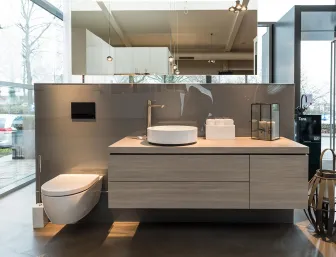 Ein modernes Badezimmer mit wandhängendem WC und einem schwebenden Waschtisch aus hellem Holzdekor.