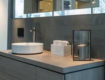 Ein stilvoller Waschtisch mit heller Holzoberfläche und rundem, weißen Aufsatzwaschbecken in modernem Design.