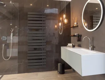 Ein edles Badezimmer mit dunkler Marmorwand und modernem Design-Heizkörper in Mattschwarz. 