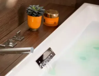 Detailansicht einer modernen Badewanne mit integrierter Armatur und Wasserfallauslauf. 