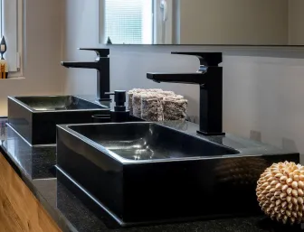 Doppelwaschtisch mit schwarzen Aufsatzbecken, schwarzen Armaturen und Holzunterschrank in modernem Bad.