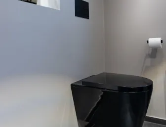 Modernes wandhängendes schwarzes WC mit minimalistischer Spülbetätigung in einem renovierten Bad.