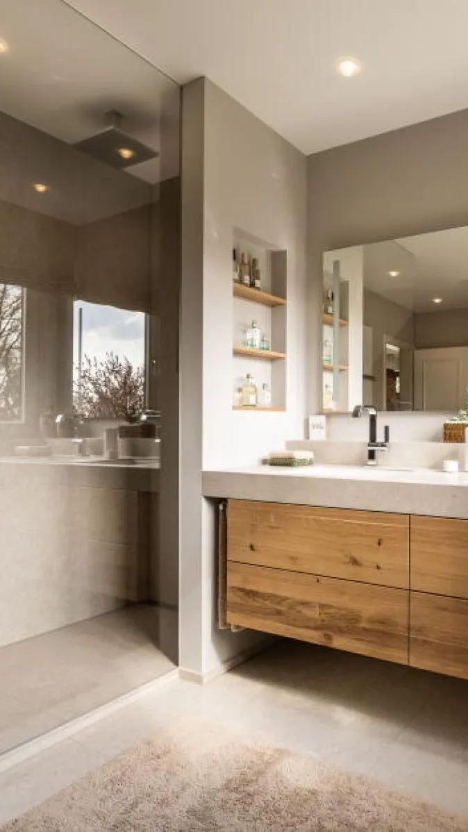 Ein modernes Badezimmer mit großer begehbarer Dusche und Glasabtrennung auf der linken Seite.