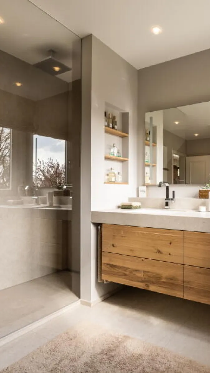 Ein modernes Badezimmer mit großer begehbarer Dusche und Glasabtrennung auf der linken Seite.