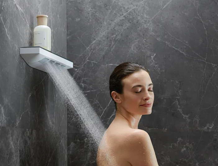 Eine Frau mit geschlossenen Augen steht entspannt unter der Rainfinity Duschbrause, die Wasserstrahlen auf ihren Rücken richtet.