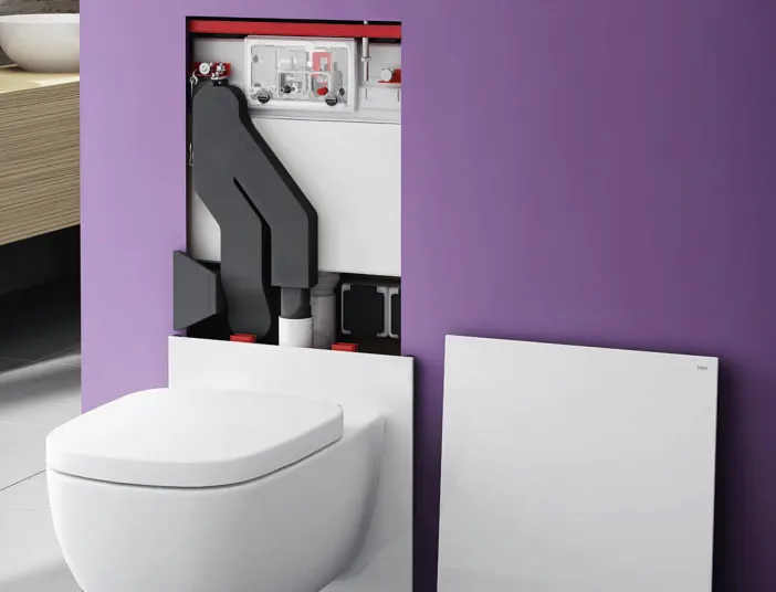 Eine wandhängende Toilette mit abgenommener Frontplatte zeigt die verborgene Installation des TECElux-Systems in einer lilafarbenen Wand. 