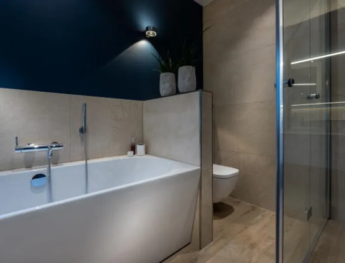 Ein modernes Badezimmer mit freistehender Badewanne, die elegant in eine Nische mit beigefarbenen Fliesen eingebettet ist.