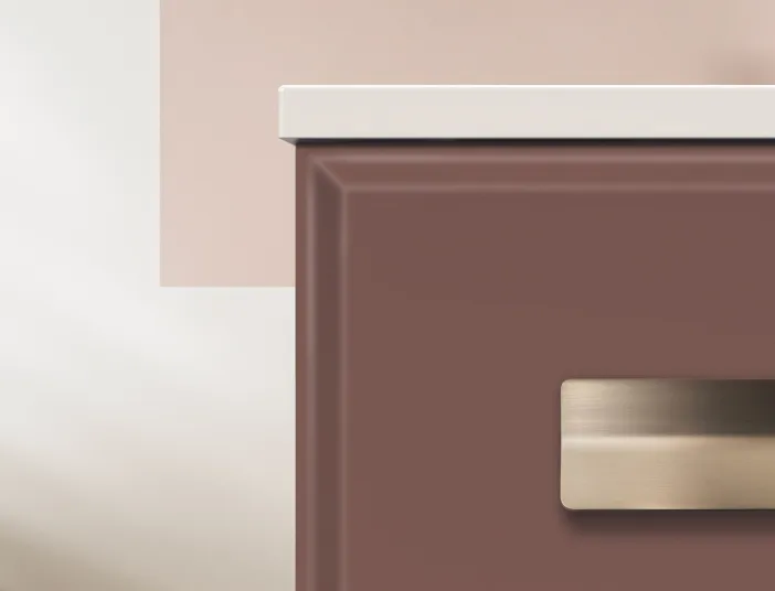 Detailaufnahme eines rosafarbenen Waschtischs mit abgeschrägter Front und gebürstetem, goldfarbenem Griff.